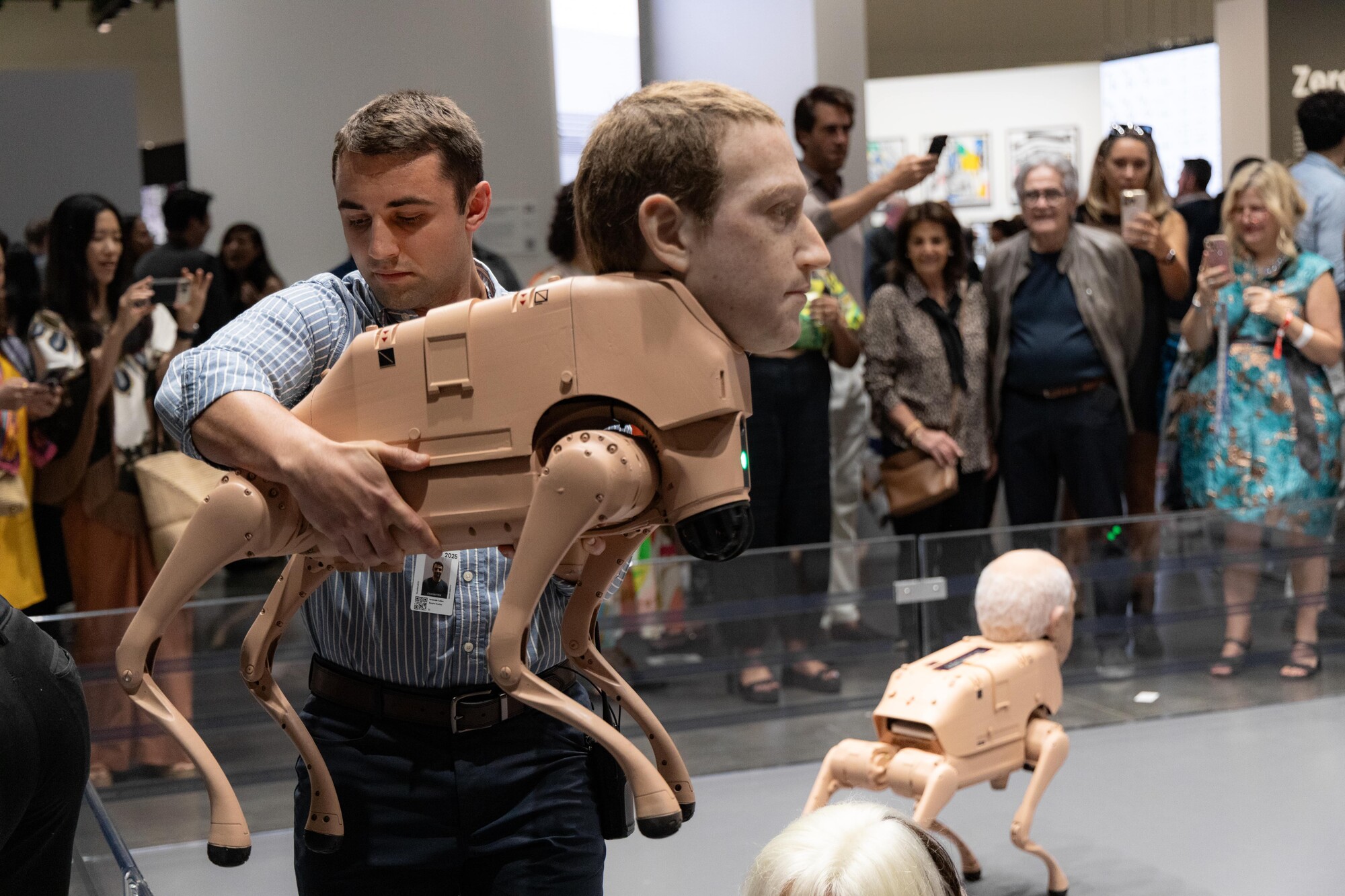 Published Art Basel photograph of Jeremiah Cullen carrying a Regular Animals robot dog, with an event badge on his shirt